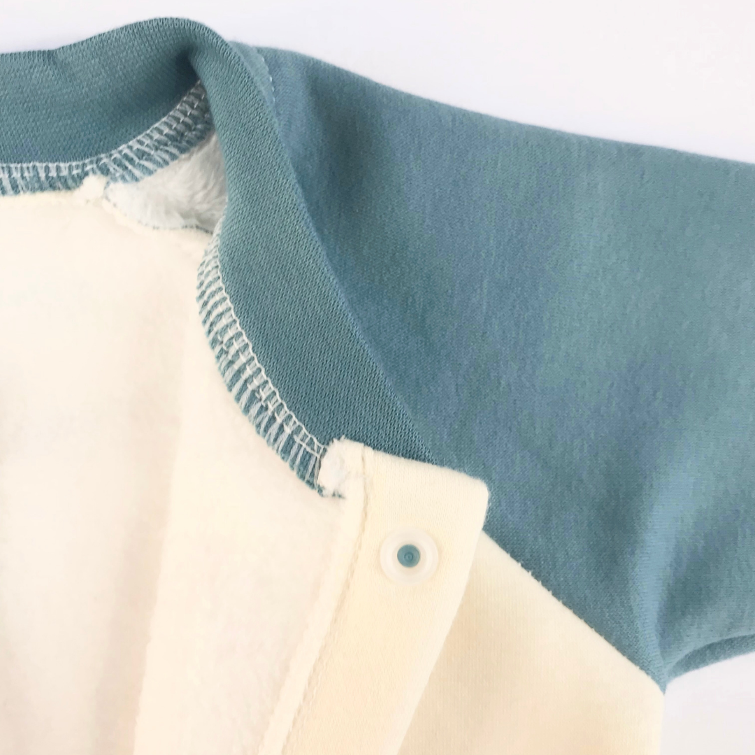 Detalle puño crema manga raglan azul petróleo