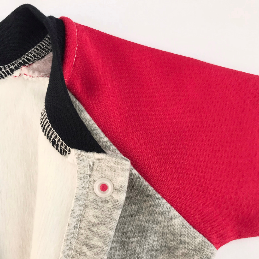 Detalle cuello azul marino y manga raglan roja con broche